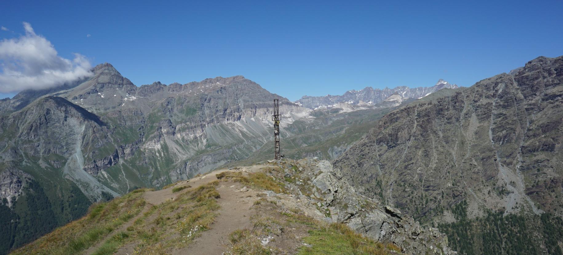 La croce di vetta del Palon di Resy con il gruppo Tournalin-Roisettaz, il Vallone delle Cime Bianche e le Grandes Murailles sullo sfondo.